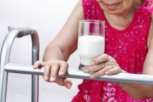 Grandmother holding a glass of milk , isolated over white backgr