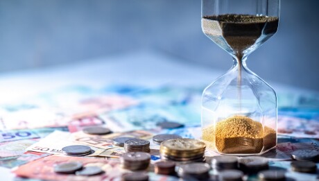 Hourglass and currency on table, Time Investment concept